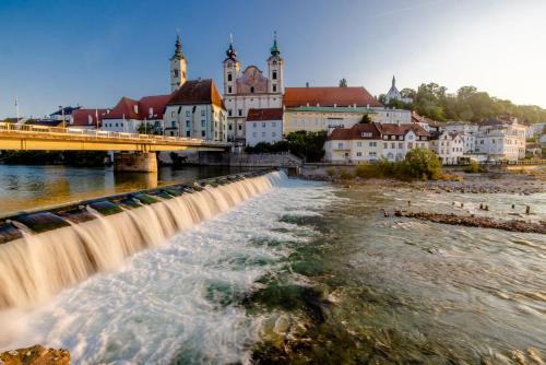 einen Fluss mit einem Wasserfall vor einer Stadt in der Unterkunft Hotel-Restaurant Minichmayr in Steyr