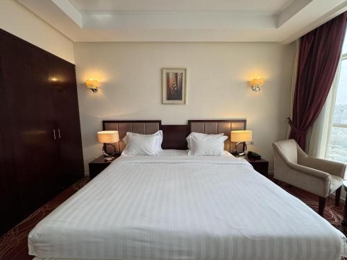 a bedroom with a large white bed with two lamps at فندق أبراج الريان المكية Al Rayyan Makiya Towers Hotel 1 in Makkah
