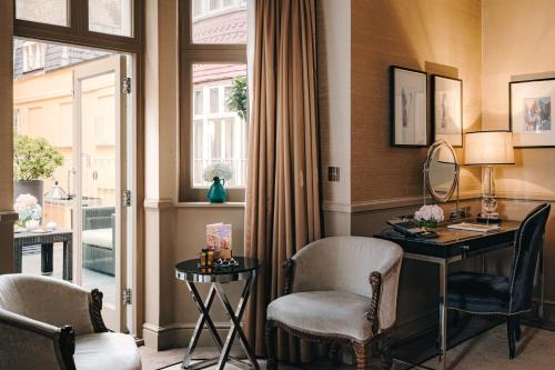 um quarto com uma secretária, cadeiras e uma janela em Althoff St James's Hotel & Club London em Londres