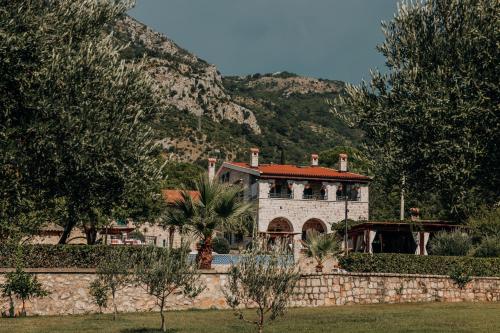 a house with a stone wall in front of a mountain at Talići Hill - Rustic Villas in Sutomore