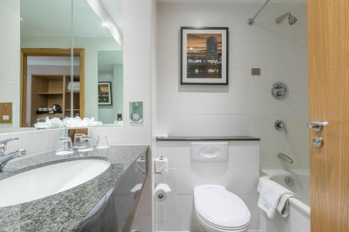 La salle de bains blanche est pourvue de toilettes et d'un lavabo. dans l'établissement Clayton Hotel Ballsbridge, à Dublin