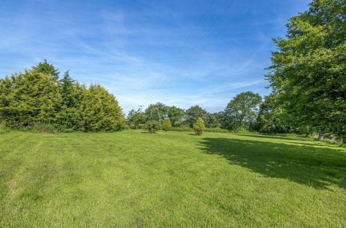 a large field of grass with trees in the background at Deer View in Bishops Tawton