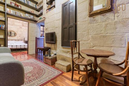 uma sala de estar com uma mesa e cadeiras e uma televisão em Charming home with Stunning City Views in Birgu by 360 Estates em Birgu