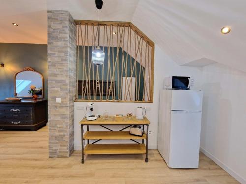 eine Küche mit einem Tisch und einem weißen Kühlschrank in der Unterkunft Le Colombier in Laon