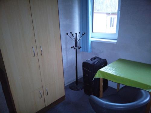 Zimmer mit einem Schreibtisch, einem grünen Tisch und einem Koffer in der Unterkunft Privates Zimmer für Übernachtung in Blankenfelde