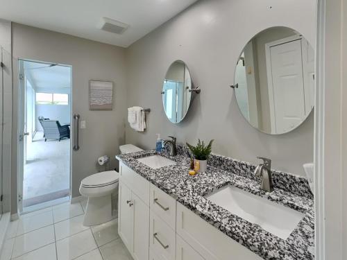 een badkamer met 2 wastafels, een toilet en een spiegel bij Coastal Castaway in Cape Coral