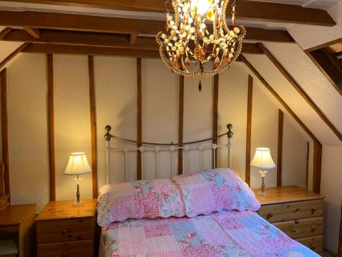 um quarto com uma cama com um lustre e 2 candeeiros em Barn Owl Cottage, The Welsh Reindeer Retreat, Ystradfach Farm , Llandyfaelog, Carmarthen , SA17 5NY em Carmarthen