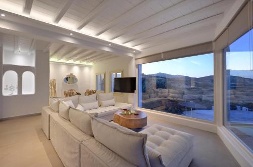 a living room with a couch and a large window at Mykonos Dream Villas in Elia