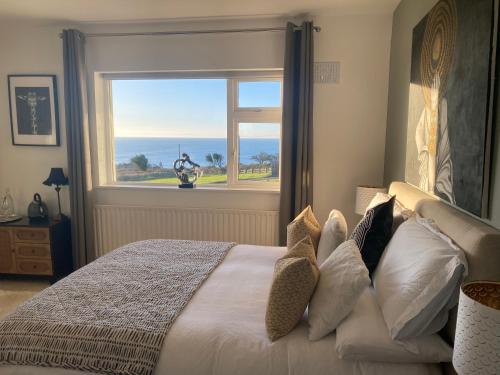 a bedroom with a bed with a view of the ocean at Follies Suites Ballyvoile in Dungarvan