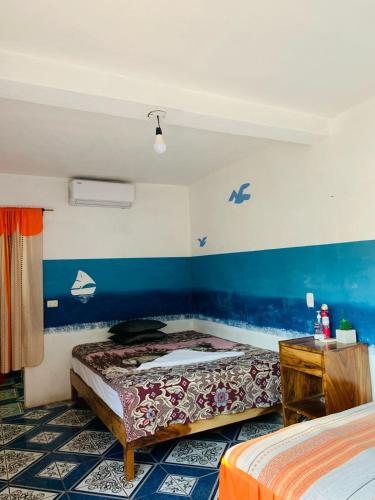 a bedroom with two beds and a blue wall at Cuarto Cactus in El Paredón Buena Vista