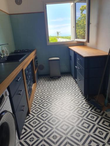 a kitchen with a white and black tile floor at Les Fauvettes in Saint-Paul