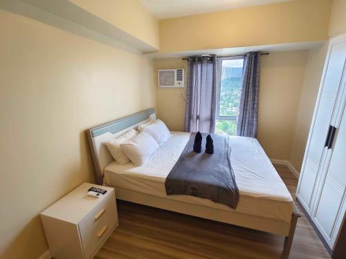 um pequeno quarto com uma cama e uma janela em Cebu Avida Riala T4 2620 IT Park em Cebu