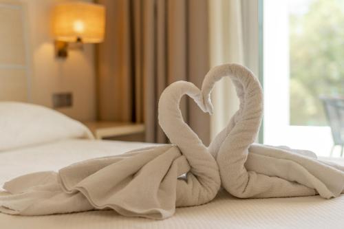 two towels shaped like swans sitting on a bed at Kamari Beach in Lardos