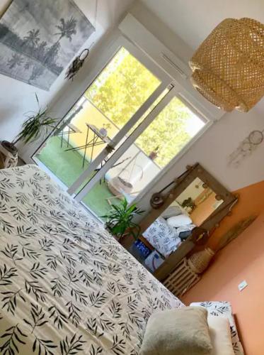 ein Schlafzimmer mit einem Bett und einem großen Fenster in der Unterkunft Superbe Appartement idéalement situé in Mérignac