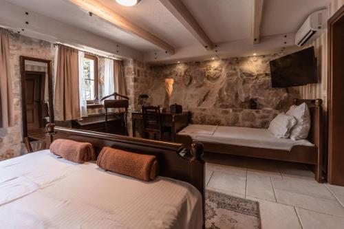 a bedroom with two beds and a tv on a wall at Talići Hill - Rustic Villas in Sutomore