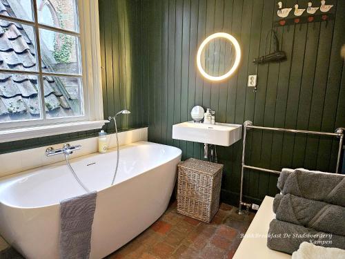 a green bathroom with a tub and a sink at De Stadsboerderij in Kampen