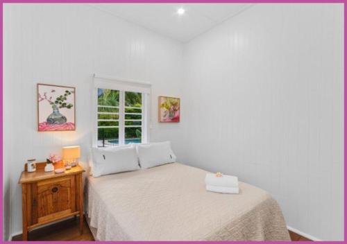 a white bedroom with a bed and a window at The Grand Queenslander On Turner in Aitkenvale