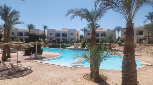 a pool with palm trees and buildings in the background at First Class at Naama Bay Hotel Appartments in Sharm El Sheikh