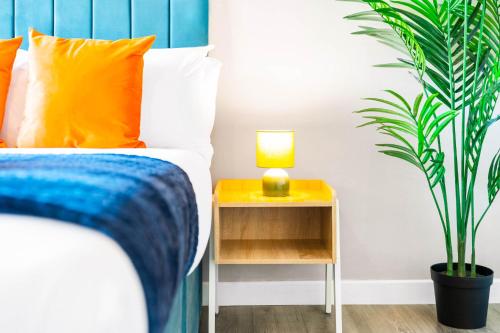 a bed with orange pillows and a lamp on a side table at Brand New Modern One Bed Cradley Heath - Top Rated - 1MH in Smethwick