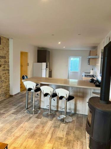 - une cuisine avec un bar avec des tabourets et une cuisinière dans l'établissement Appartement cocooning, à Saint-Martin-des-Fontaines