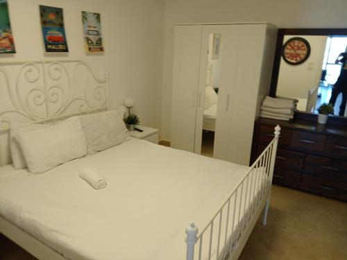 a bedroom with a white bed and a mirror at Marina towers in Herzelia 