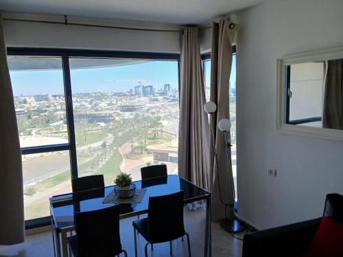 uma sala de jantar com mesa e cadeiras e uma grande janela em Marina towers em Herzelia 