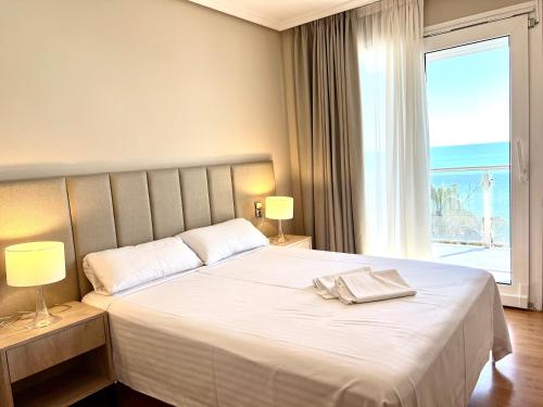 a bedroom with a large white bed with a window at Apartamentos las Palmas VII Family only in Salou