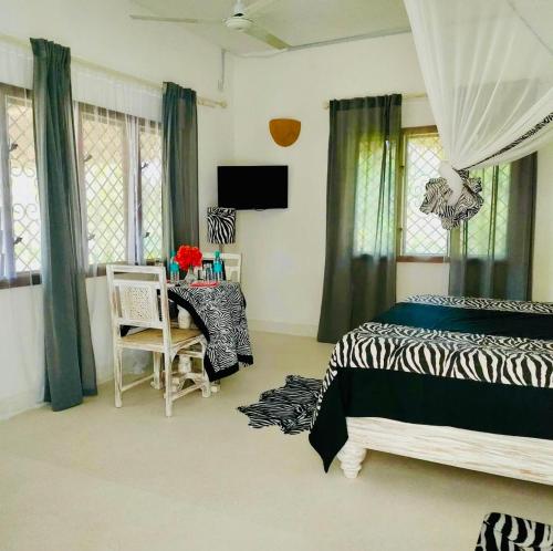a bedroom with a bed and a table and chairs at WHITE Nyumba in Malindi