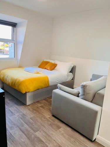 - une petite chambre avec un lit et un canapé dans l'établissement Cozy Studio in Maidstone Town Centre, à Kent
