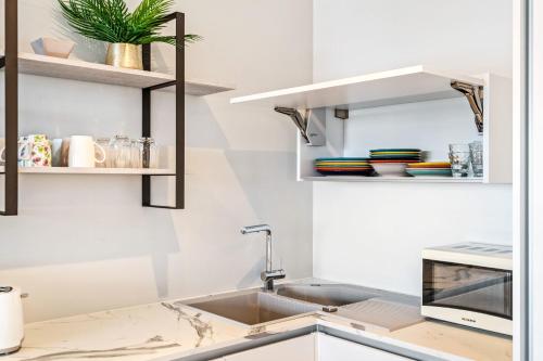 a kitchen with a sink and a microwave at Gasperich Apt with Pool Gym & View in Luxembourg