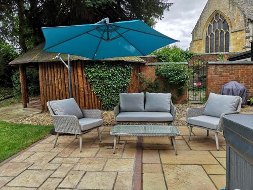 un patio con 2 sillas y una sombrilla azul en The Old Rectory, en Sedgeberrow