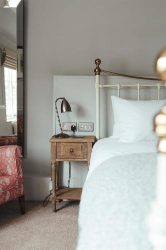 a bedroom with a bed and a table with a lamp at The Woolpack Hotel in Tenterden