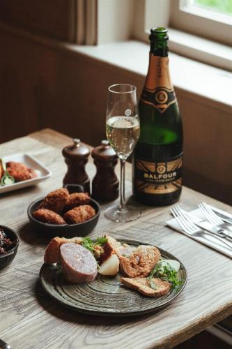 a table with a plate of food and a bottle of wine at The Woolpack Hotel in Tenterden