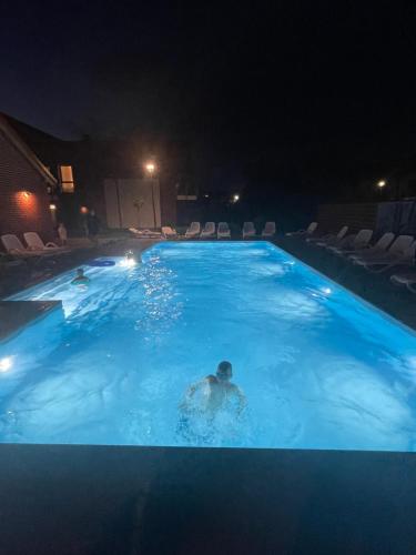 a man swimming in a swimming pool at night at Apartament Łeba Piaskowa Ostoja in Żarnowska