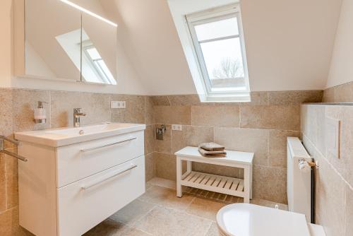 a bathroom with a sink and a toilet and a window at White House Ferienwohnung 2 in Alkersum