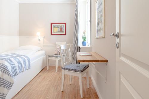 ein kleines Schlafzimmer mit einem Bett und einem Schreibtisch in der Unterkunft Haus Uthlande Wohnung 25 in Wyk auf Föhr