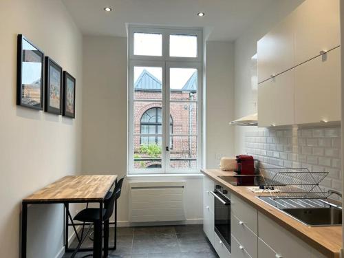 une cuisine blanche avec une table et une fenêtre dans l'établissement Vieux-Lille Appartement rénové avec une chambre, à Lille