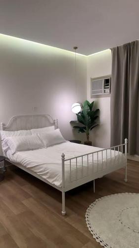 uma cama branca num quarto com uma planta em شقة واسعه بتصميم حديث em Al Fayşalīyah