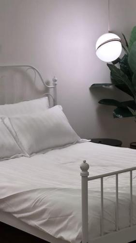 1 dormitorio con 1 cama blanca con lámpara y planta en شقة واسعه بتصميم حديث, en Al Fayşalīyah