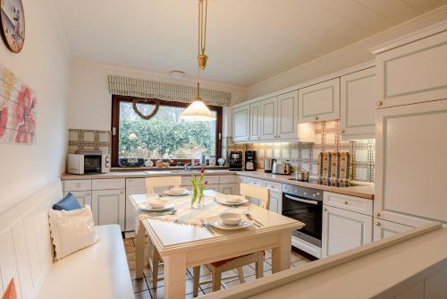 a kitchen with white cabinets and a table in it at White House Ferienwohnung 1 in Alkersum
