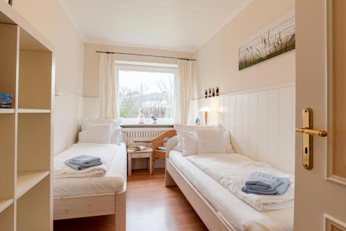two beds in a small room with a window at White House Ferienwohnung 1 in Alkersum