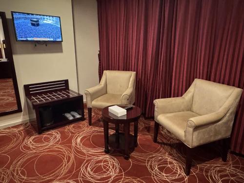 a room with two chairs and a table and a tv at فندق أبراج الريان المكية Al Rayyan Makiya Towers Hotel 1 in Makkah