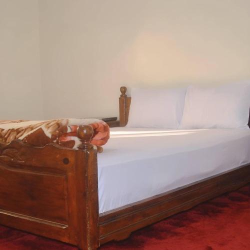 ein Bett mit weißer Bettwäsche und einem Holzrahmen in der Unterkunft Tililt house 