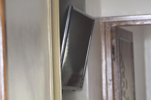 einen Fernseher, der an einer Wand neben einem Spiegel hängt in der Unterkunft Tililt house 
