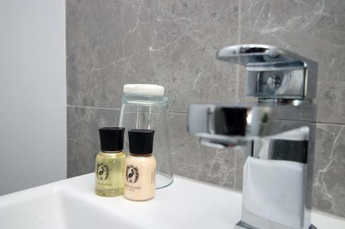 two bottles of disinfectants sitting on a bathroom sink at Modern Cardiff Retreat 3BR with Netflix & High-Speed Wifi in Cardiff