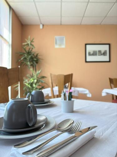 a table with silverware on a white table cloth at Hôtel Restaurant d'Occitanie in Toulouse