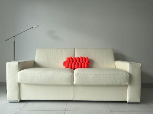 a white couch with two red pillows on it at Oasis tout confort à Bergheim, Alsace in Bergheim
