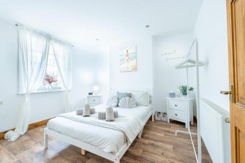 a white bedroom with a bed and two windows at Seaside serenity in our charming 1-bedroom retreat in Kent