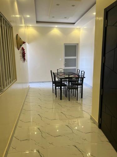 a dining room with a table and chairs on a marble floor at Résidence Mounir in Thiès