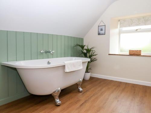 a white bath tub in a green bathroom with a window at Nempnett Farmhouse in Bristol